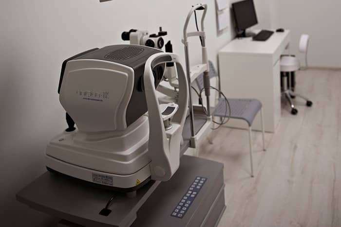 Gabinet z refraktometrem i lampą szczelinową, wyposażony w niezbędny sprzęt do przeprowadzania badań optometrycznych.