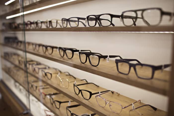 Oprawy okularowe ustawione w równym rzędzie na półce w salonie optycznym oferujące szeroki wybór dla potencjalnych nabywców.